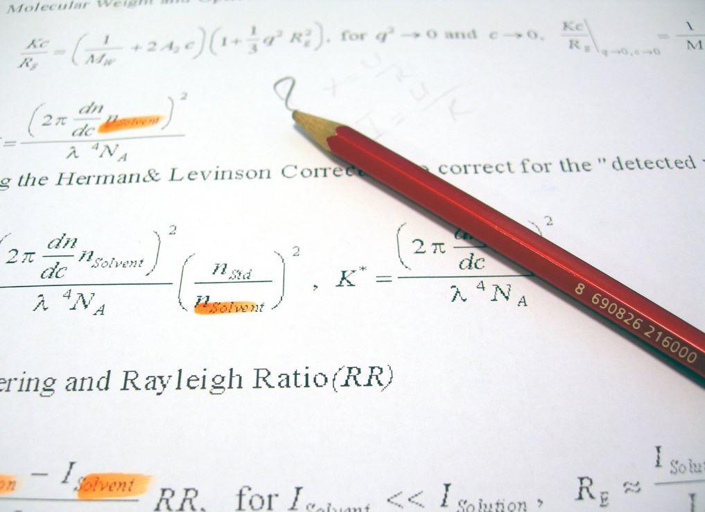 A red pencil sitting on a sheet of mathematical formulas